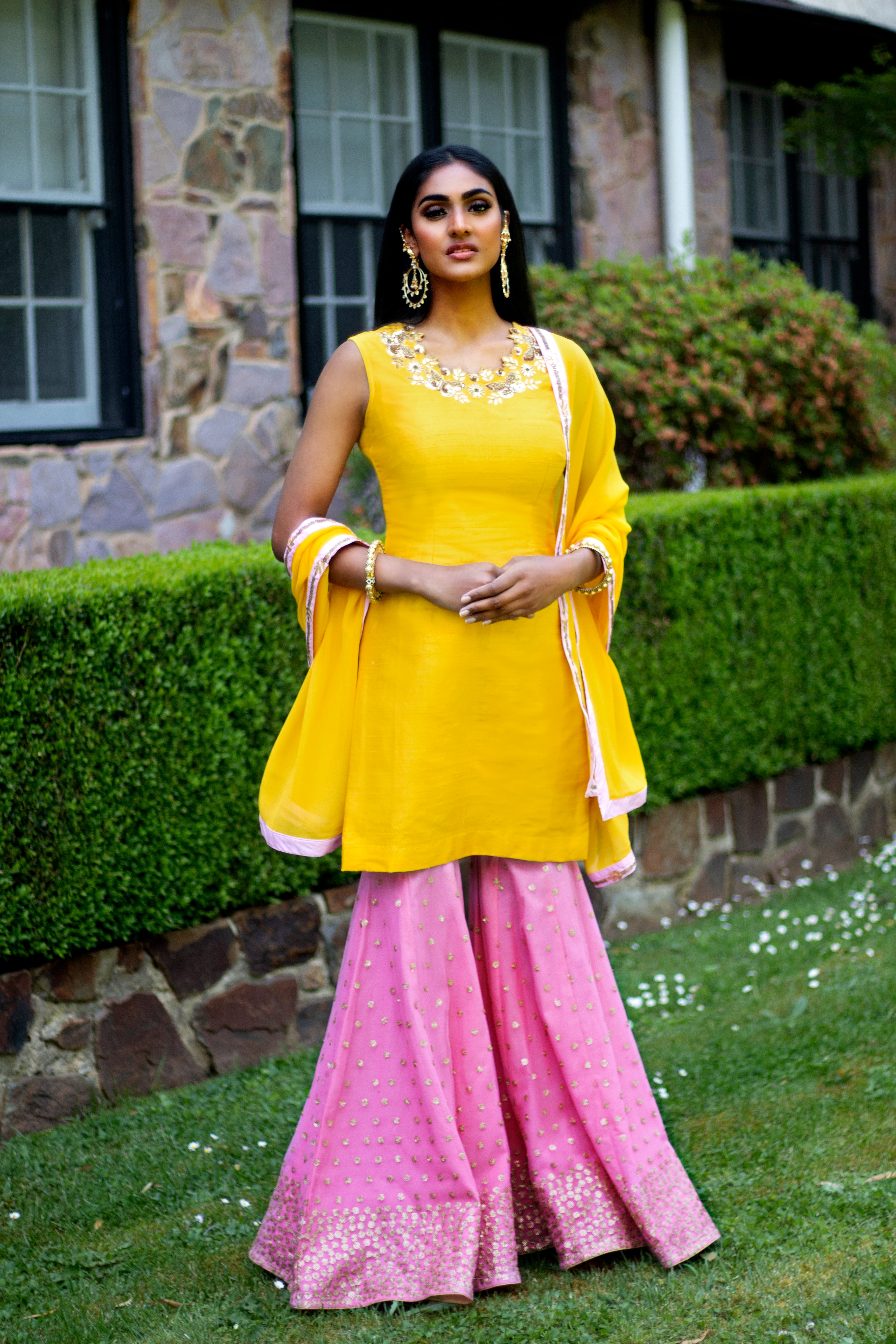 Yellow and pink Rani Gharara Sharara by Couture Mantra, featuring intricate embroidery and flowy fabric for traditional elegance.