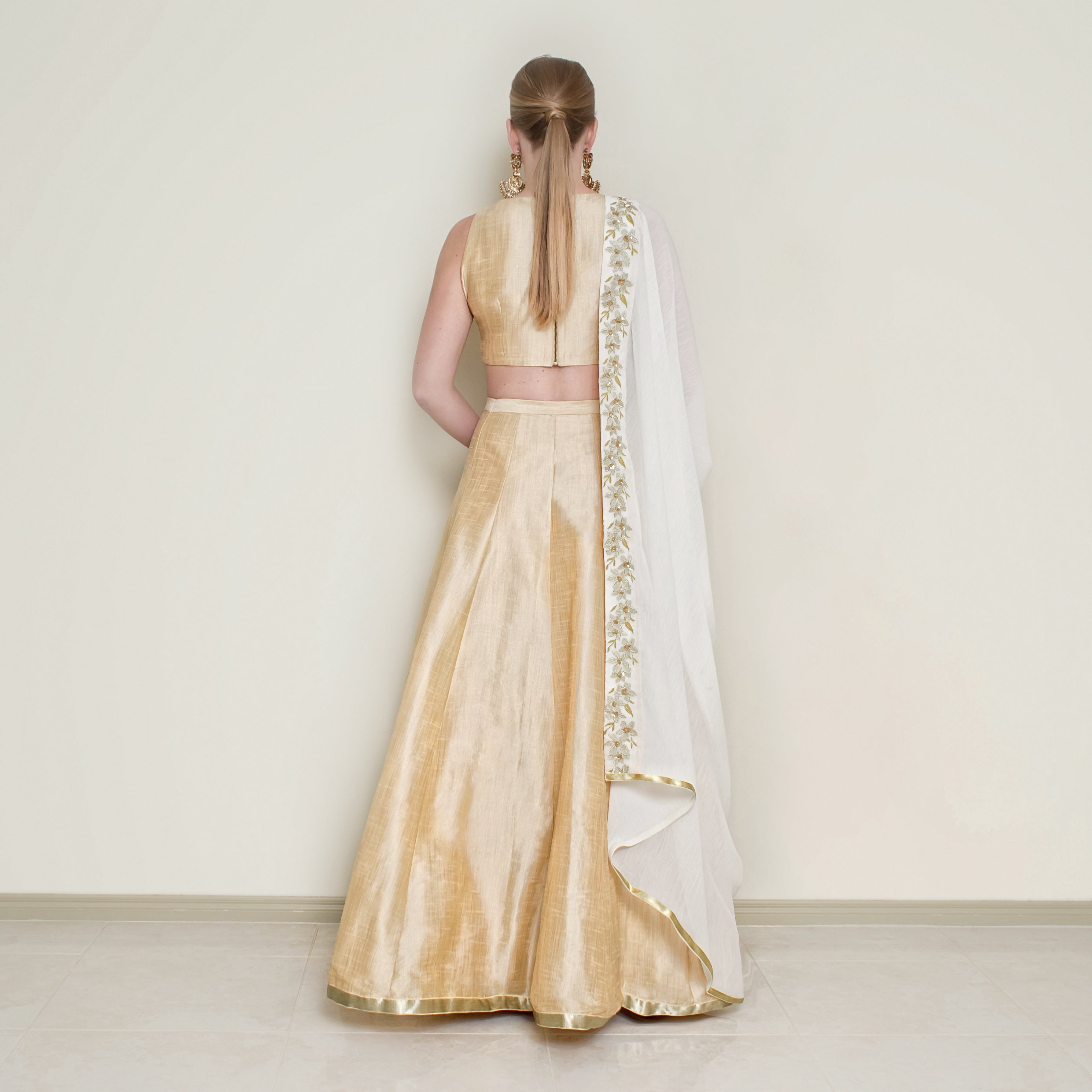 Cream halter neck lehenga set by Nakir featuring intricate embroidery and flowing fabric, perfect for traditional celebrations.