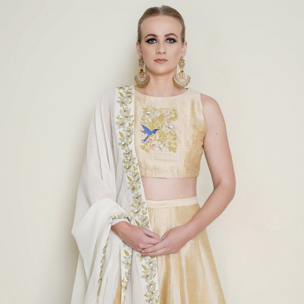 Cream halter neck lehenga set by Nakir featuring intricate embroidery and a flowing skirt, perfect for festive occasions.