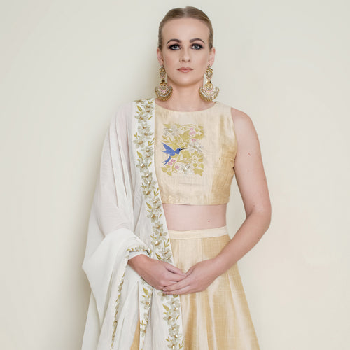 Cream halter neck lehenga set by Nakir featuring intricate embroidery and a flowing skirt, perfect for festive occasions.