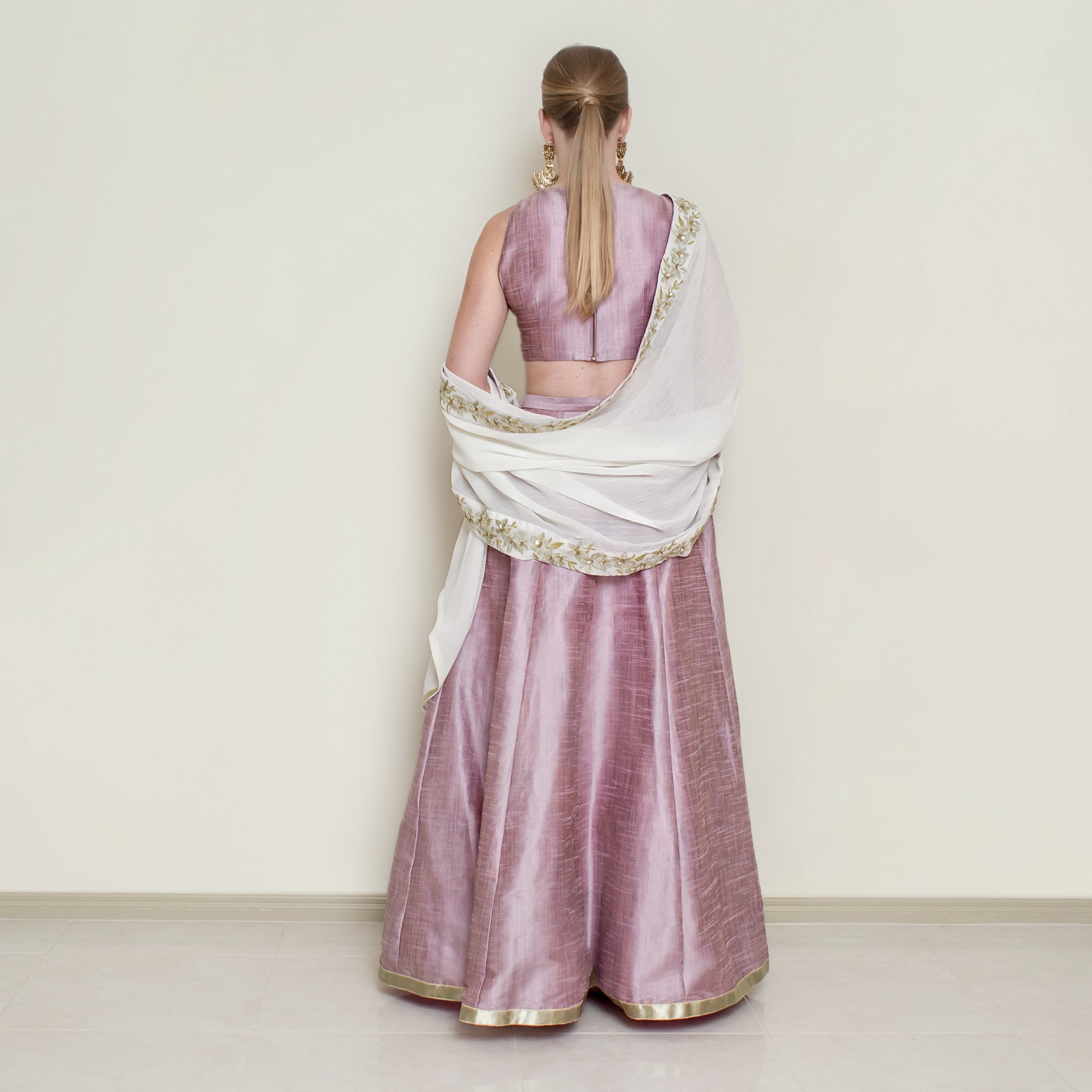 Pink halter neck lehenga set by Nakir featuring intricate embroidery and flowing fabric, perfect for traditional celebrations.