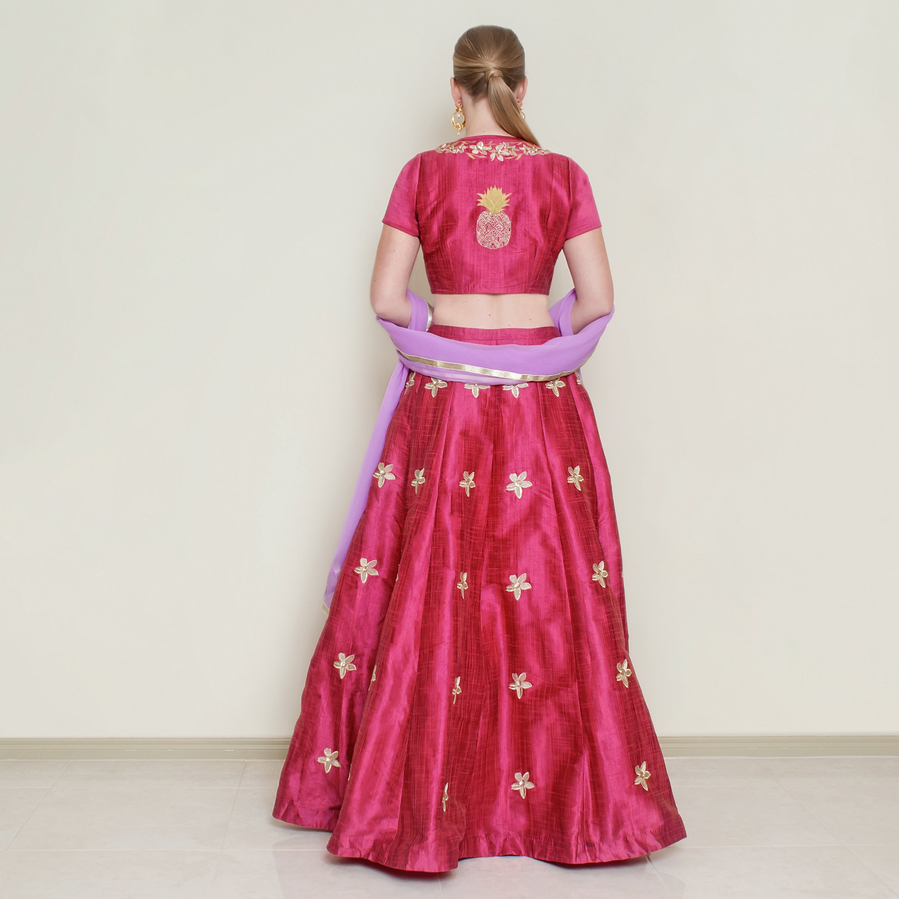 Red pineapple lehenga set by Nakir featuring intricate embroidery and a flowing choli for traditional festive wear.