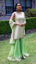 Rani beige and green sharara from Couture Mantra featuring intricate embroidery and flowing fabric for traditional festive wear.